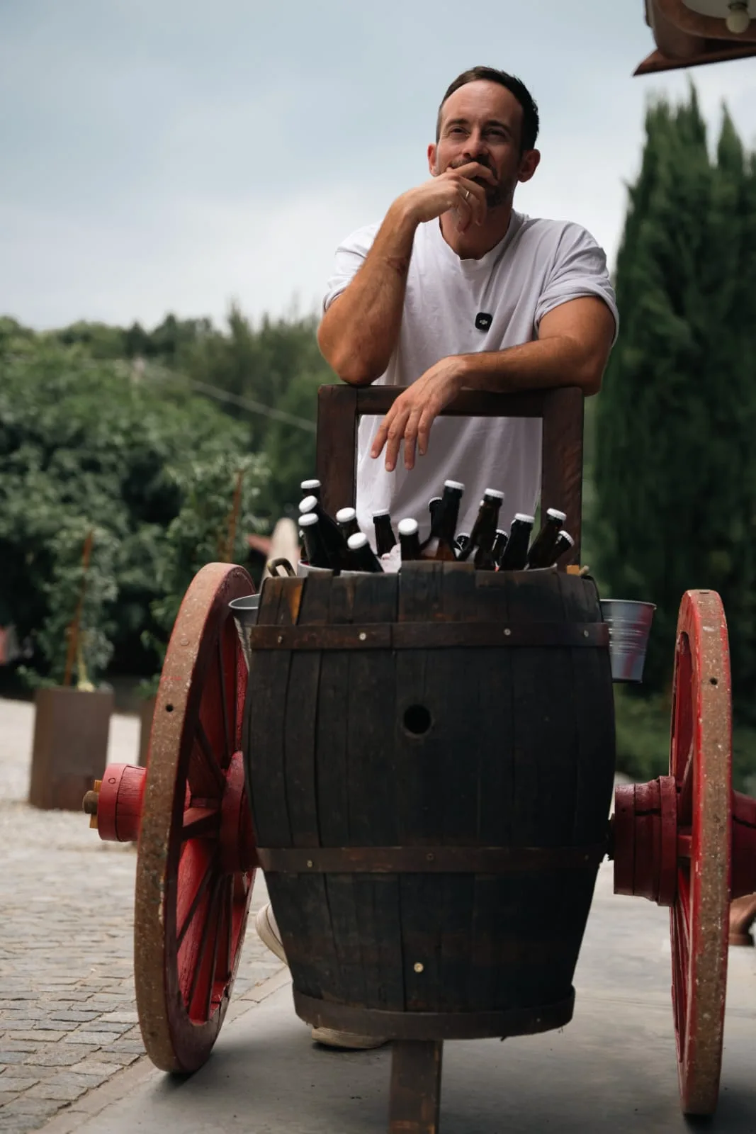 Un uomo appoggiato al carretto con la botte piena di birre artigianali