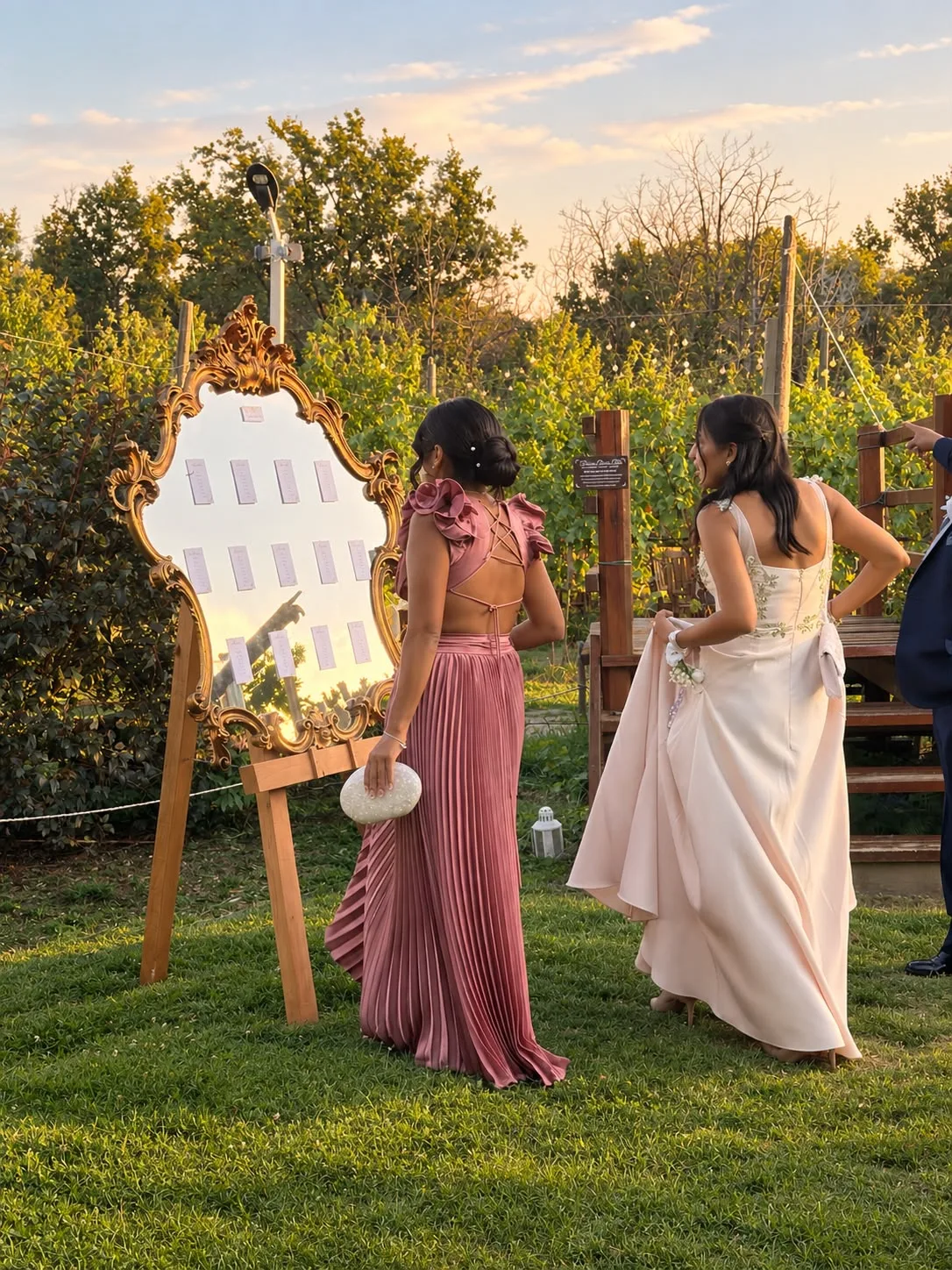 Due invitate guardano il tableau dei tavoli su uno specchio dorato al tramonto